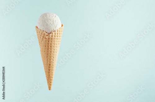 White creamy ice cream in crisp waffle cone on soft light pastel green background, mock up, copy space. © finepoints