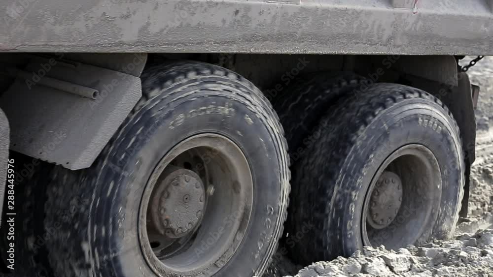 Dirty truck goes through dirt of construction site, wheels are buried, soft soil Dirty truck goes through dirt of construction site, wheels are buried, soft soil