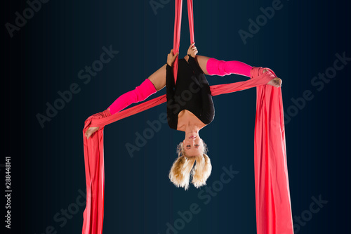 Beautiful acrobatics woman gymnast with gymnastic aerial silks in the gym.