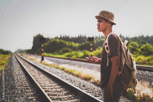 man with backpack walking away on railroad and emphasize to patience and survey trying step forward to goal. copy space