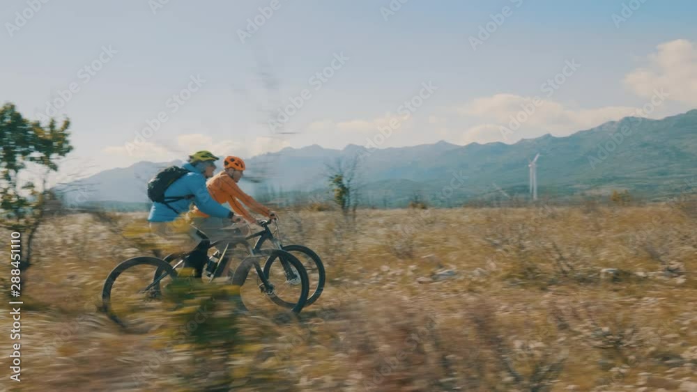 Tracking shot of two friends cycling on a sunny day Tracking shot of two friends cycling on a sunny day