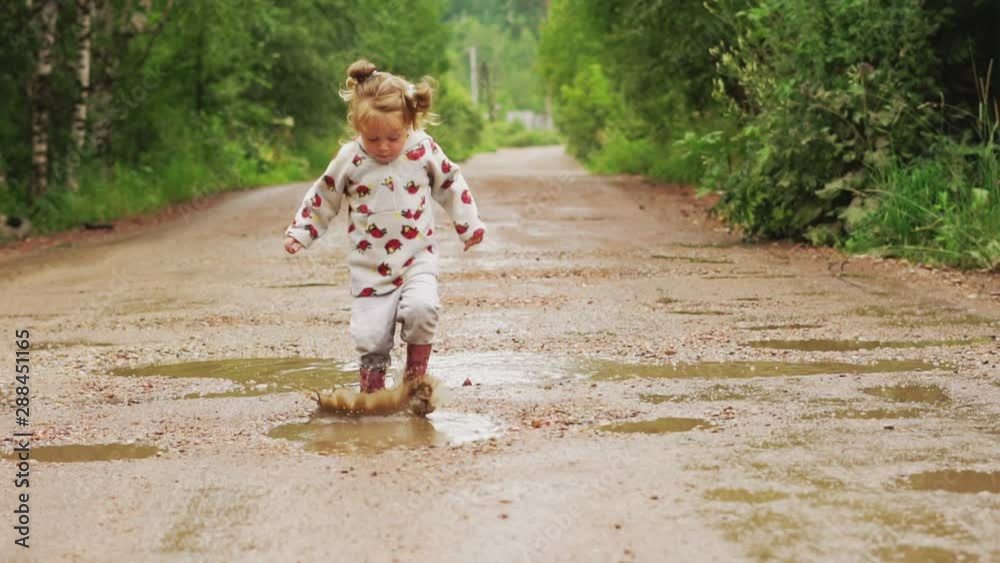 the child runs through puddles in rubber boots the child runs through puddles in rubber boots