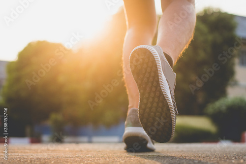 Close up. leg. sunlight. man with runner on the street be running for exercise