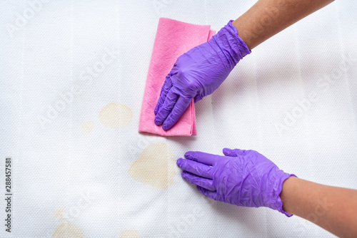 Women hands clean a dirty mattress with stains