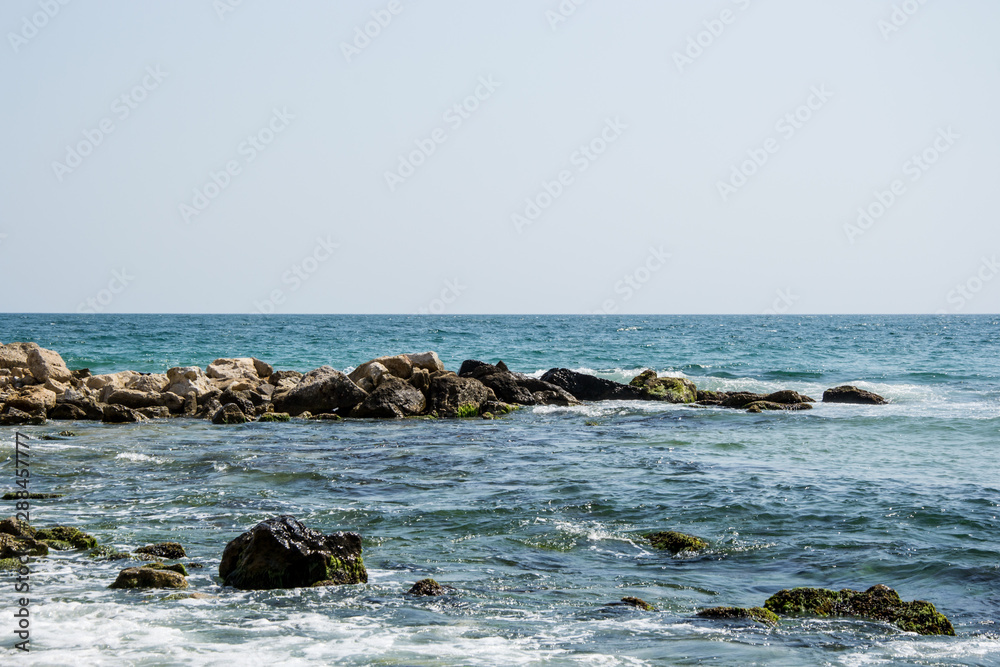 Beautiful wild beach landscape, sunny day, water waves hitting the cliffs, nature summertime scene Beautiful wild beach landscape, sunny day, water waves hitting the cliffs, nature summertime scene