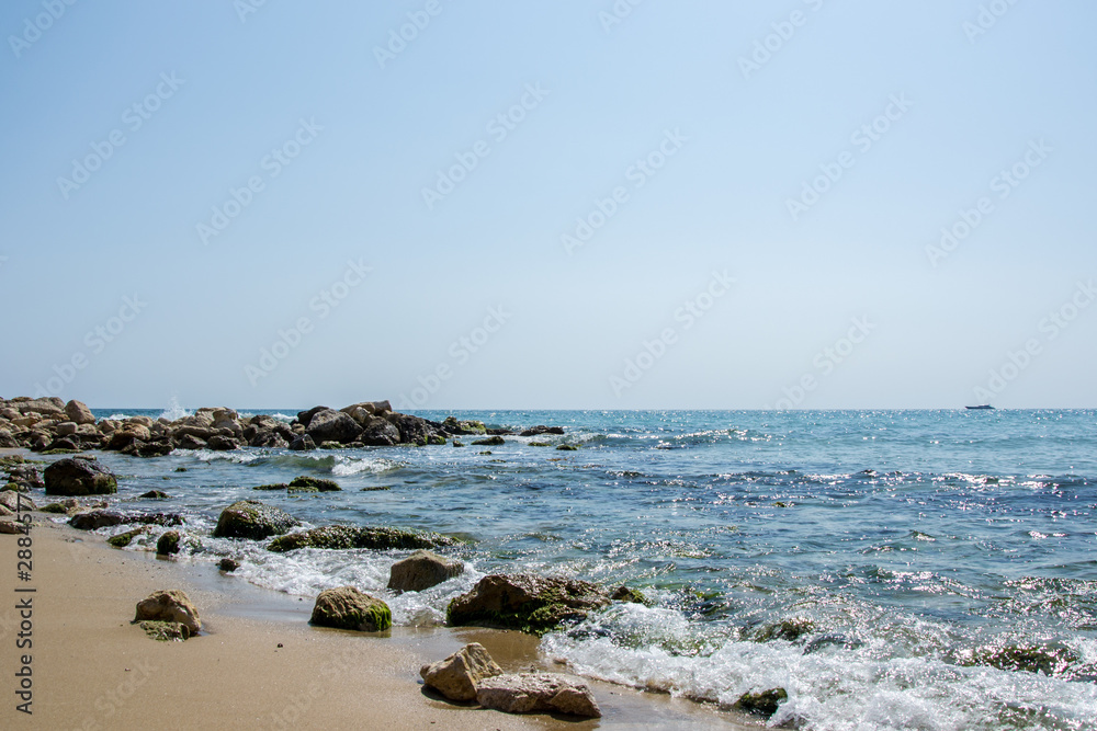 Beautiful wild beach landscape, sunny day, water waves hitting the cliffs, nature summertime scene Beautiful wild beach landscape, sunny day, water waves hitting the cliffs, nature summertime scene