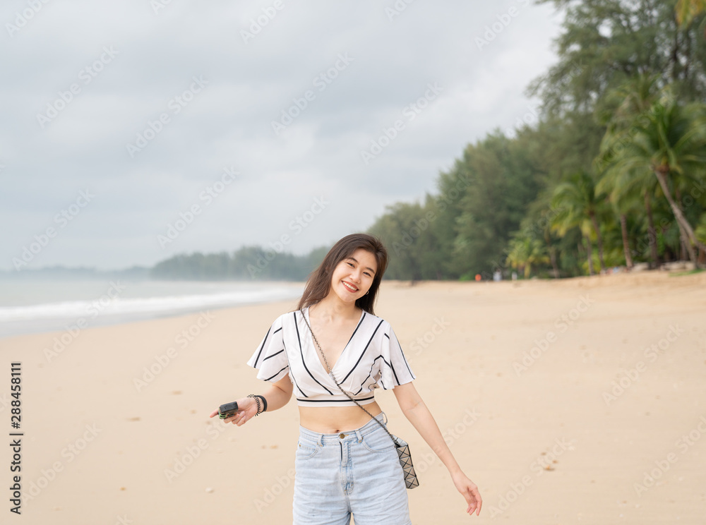 Happy women walking on the beach while emjoying taking picture / travel concept / woman on the beach Happy women walking on the beach while emjoying taking picture / travel concept / woman on the beach