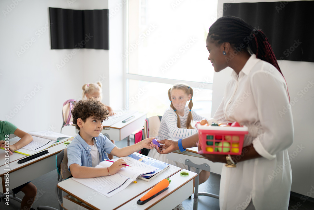 Curly dark-haired boy getting appraisal from teacher Curly dark-haired boy getting appraisal from teacher