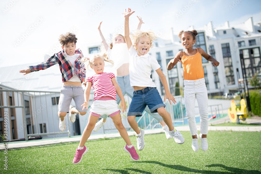 Fototapeta premium Children jumping high while having fun outside after lessons over