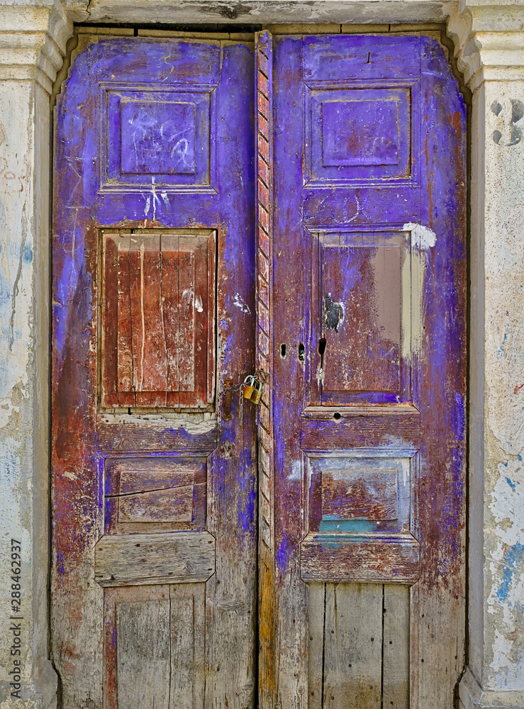 Old aged stained wooden door with chain and padlocks.