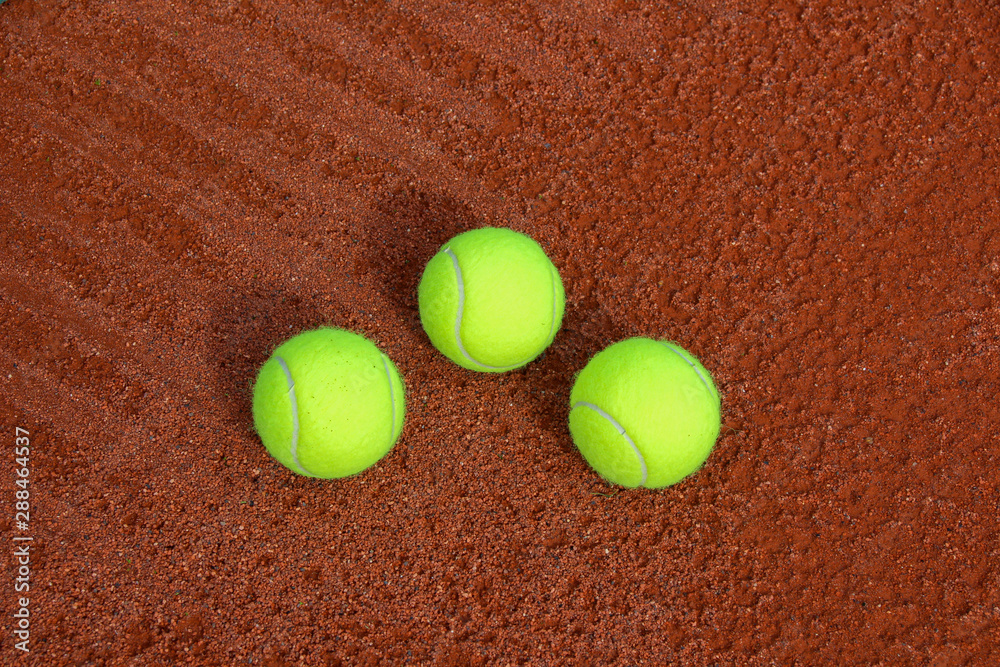 three yellow tennis balls on a tennis court