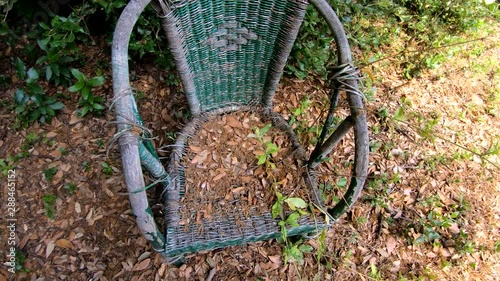 4K Right side moving left pan abandoned plastic chair in woods on bright summer day photo