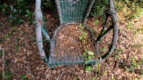 4K Ascending tilt down abandoned plastic chair in woods on bright summer day photo