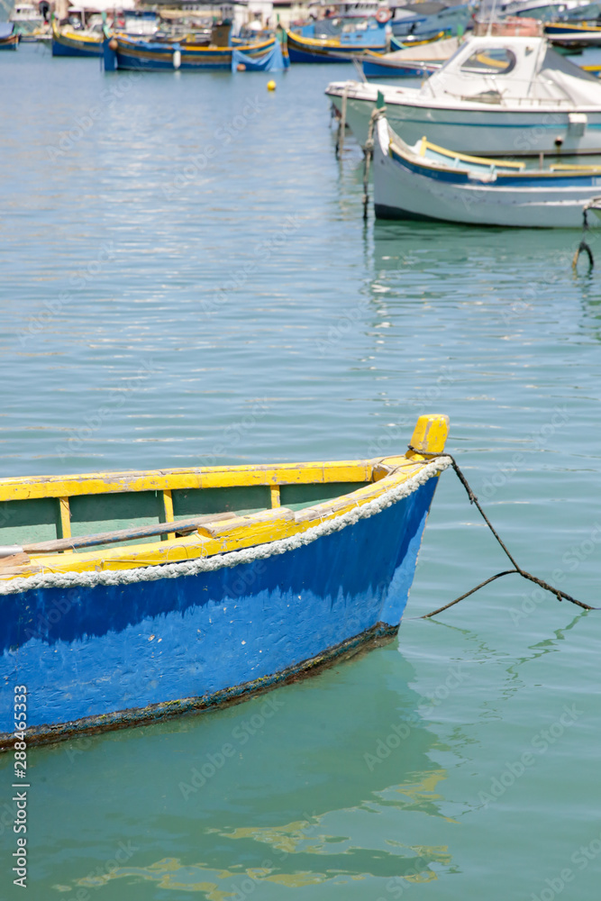 Small blue fishing boat in the clean water, water bay in Marsaxlokk, Malta's largest fishing village 
