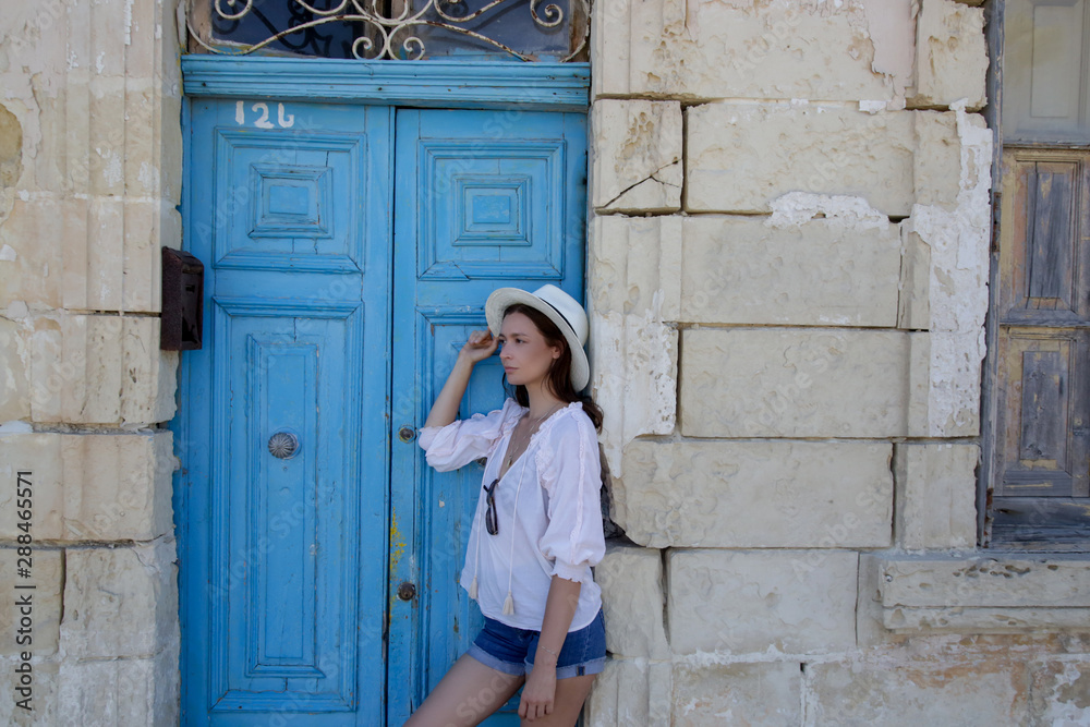 A casual fashion portrait of a young tourist woman in a summer outfit on the street