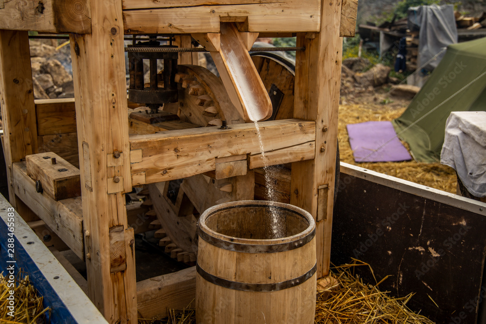 old wooden mill medieval technology with falling chopped flour into barrel, historical open air festival event old wooden mill medieval technology with falling chopped flour into barrel, historical open air festival event