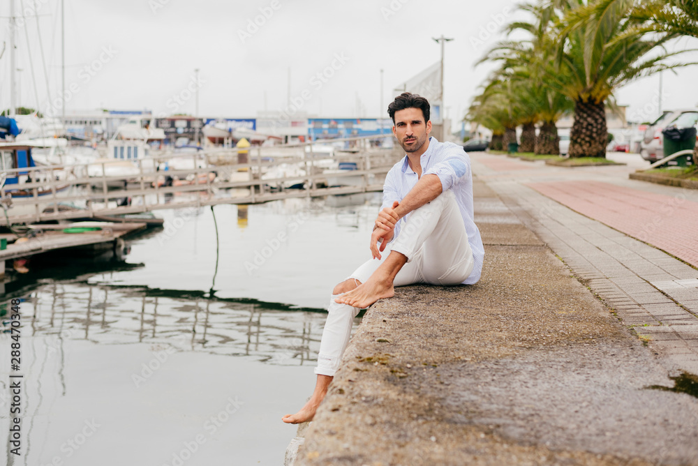 Handsome and stylish man sitting on the dock