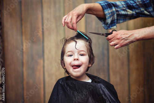 A little boy is trimmed in the hairdresser's