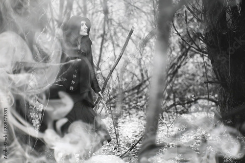 Woman in a witch suit in a dense forest