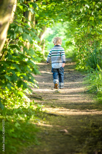Happy child running in a spring forest lit by sunlight