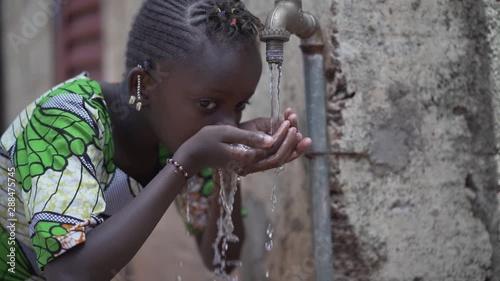 Candid Video of African Schoolgirl drinking Safe water from tap outdoors in Bamako, Mali photo