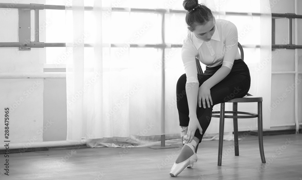 Young ballet dancer on a warm-up. The ballerina is preparing to perform in the studio. A girl in ballet clothes and shoes kneads by the handrails. Young ballet dancer on a warm-up. The ballerina is preparing to perform in the studio. A girl in ballet clothes and shoes kneads by the handrails.