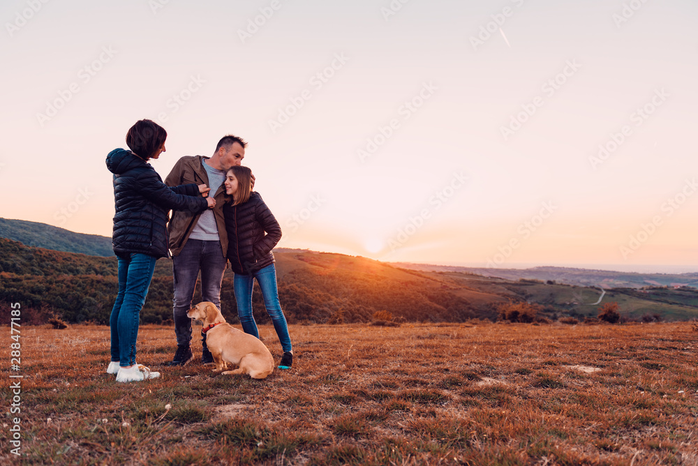 Family with dog embracing while standing on the hill