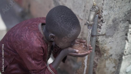 Young African Schoolboy Drinking Fresh Clean Water, Poverty Symbol