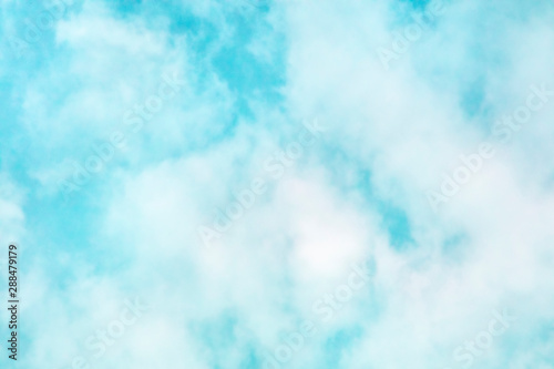 Abstract background of a vibrant clear blue teal sky with soft white clouds