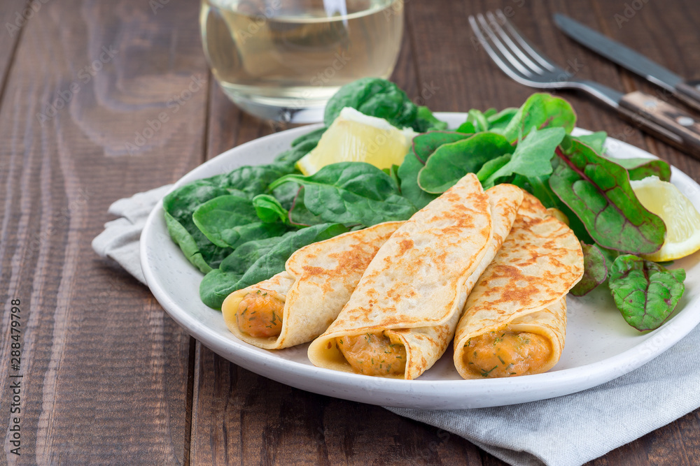 Savory crepe with shrimps and creamy dill sauce served with green leaves salad and lemon, horizontal, copy space Savory crepe with shrimps and creamy dill sauce served with green leaves salad and lemon, horizontal, copy space