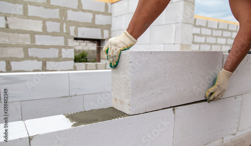 A worker lays foam concrete bricks in a house under construction photo