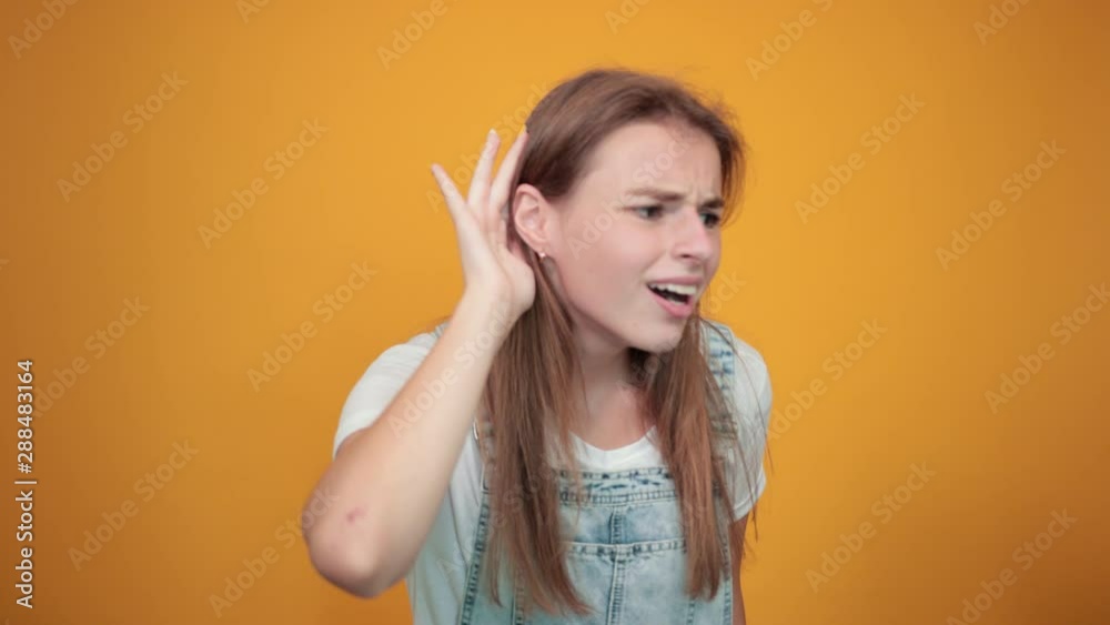 Young woman wearing white t-shirt, over orange background shows emotions