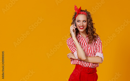 funny cheerful woman with phone on yellow background.