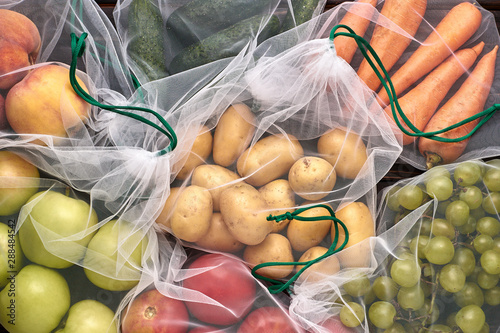 Fruits and vegetables in reusable eco-friendly bags on wooden background.Close-up. Zero waste shopping concept. Ecological concept. Refuse plastic. Stop pollution. photo