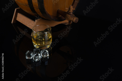 Wallpaper Mural Whiskey with ice in glass on black background. old oak barrel Torontodigital.ca