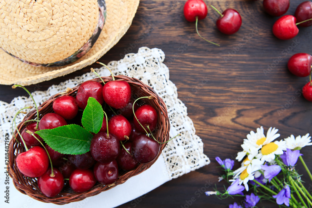 Red Cherries and summer straw hat on brown wooden table. Red Cherries and summer straw hat on brown wooden table.