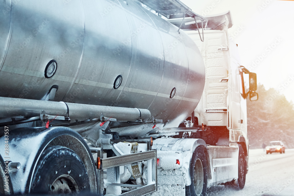 Truck with cargo tank on slippery snow winter road outside the city