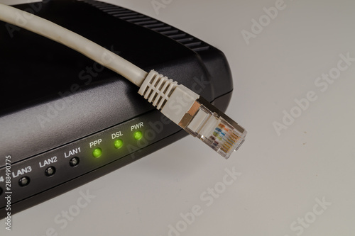 Black dsl modem or router with a network cable on a table. Concept picture for internet, wlan or mobil connections.