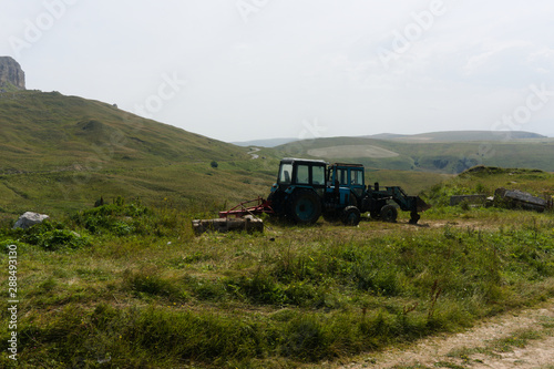 farm tractor on lawn meadows in the caucasus landscape near mount elbrus at the gumbashi pass