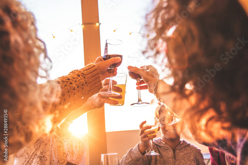 Greetings with family and friends, group of people enjoying evening drinks at end summer sunset. Hands that hold various glasses. Concept of vacation, carefree, relaxation, celebration and well-being.