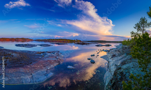 Russia. Panorama Of Karelia. Skerries of lake Ladoga. Northern nature. Evening in Karelia. Rocky Islands and pine trees. Sunset on lake Ladoga. Stones protrude from the water.