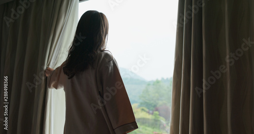 Woman wake up at morning and open the curtain at hotel room