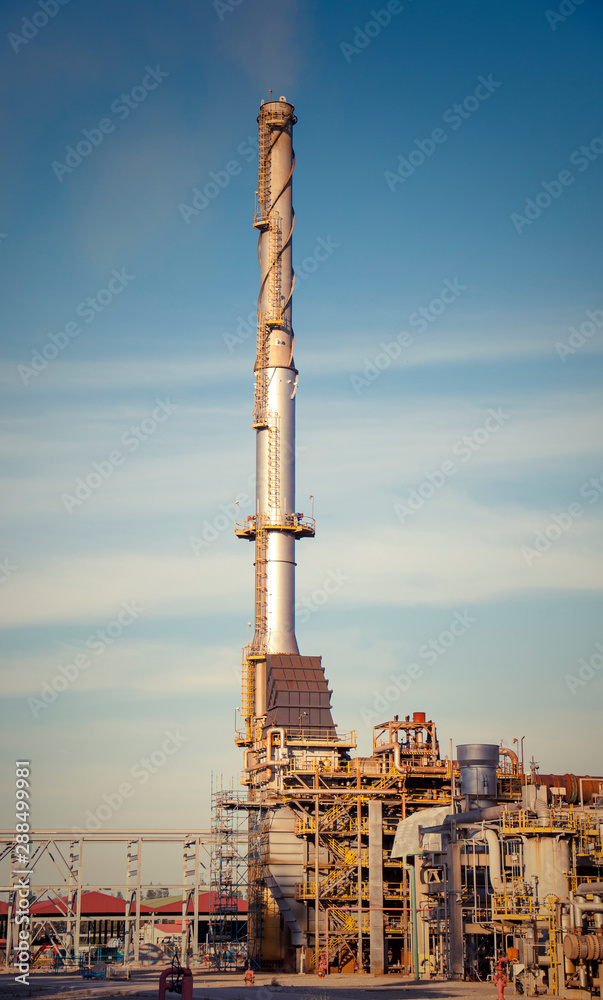 The modern factory smokestacks of the industry on the blue sky on the sunset scene The modern factory smokestacks of the industry on the blue sky on the sunset scene