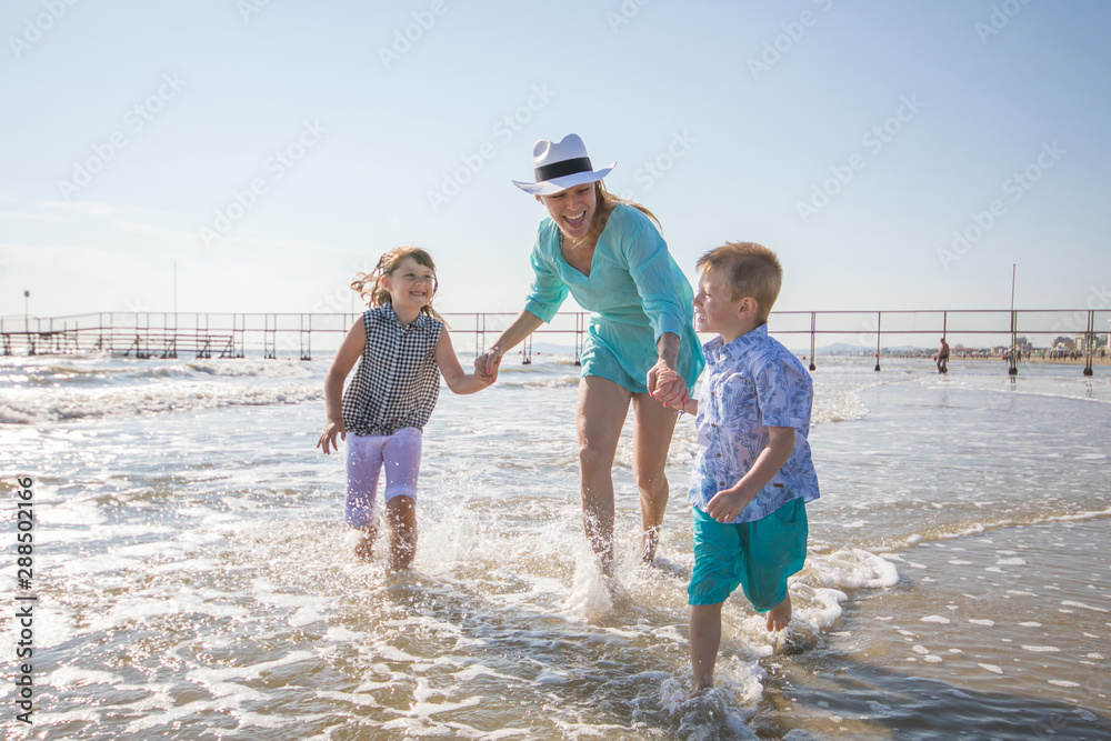 mother and children are playing in the sea on the beach mother and children are playing in the sea on the beach