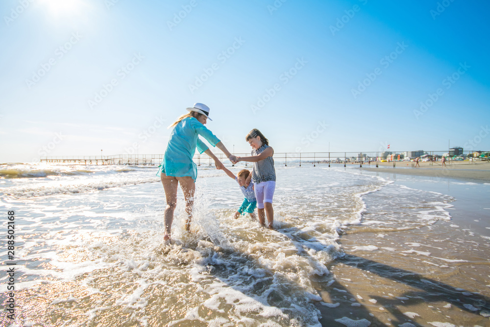 mother and children are playing in the sea on the beach