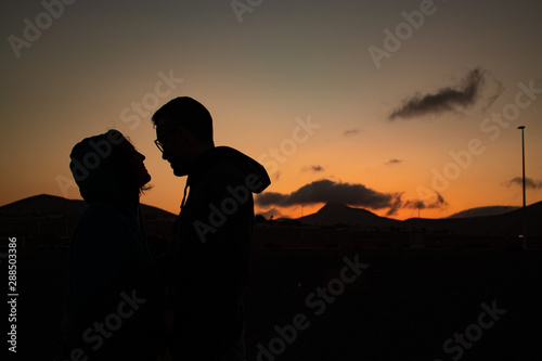 happy couple at sunset with mountain and clouds