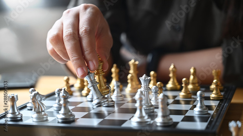 Strategy or leadership concept, Hand of business moving chess figure in competition success with closeup shot.