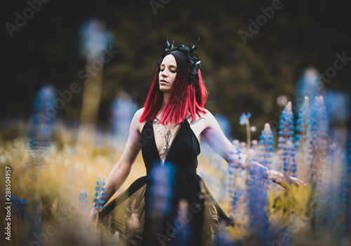 Foto Tätowiertes Model im Maleficent Look zwischen blauen Blumen