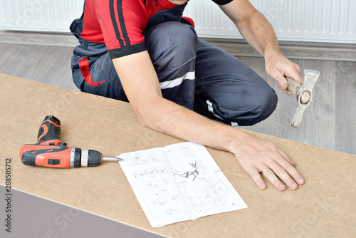 Close-up of the process of installation a furniture. Man's hands working with a screwdriver.