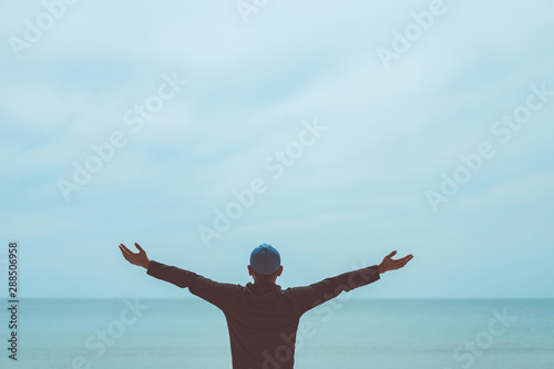 Fototapeta Naklejka Na Ścianę i Meble -  Copy space of man raise hand up on blue sky at beach and island background.